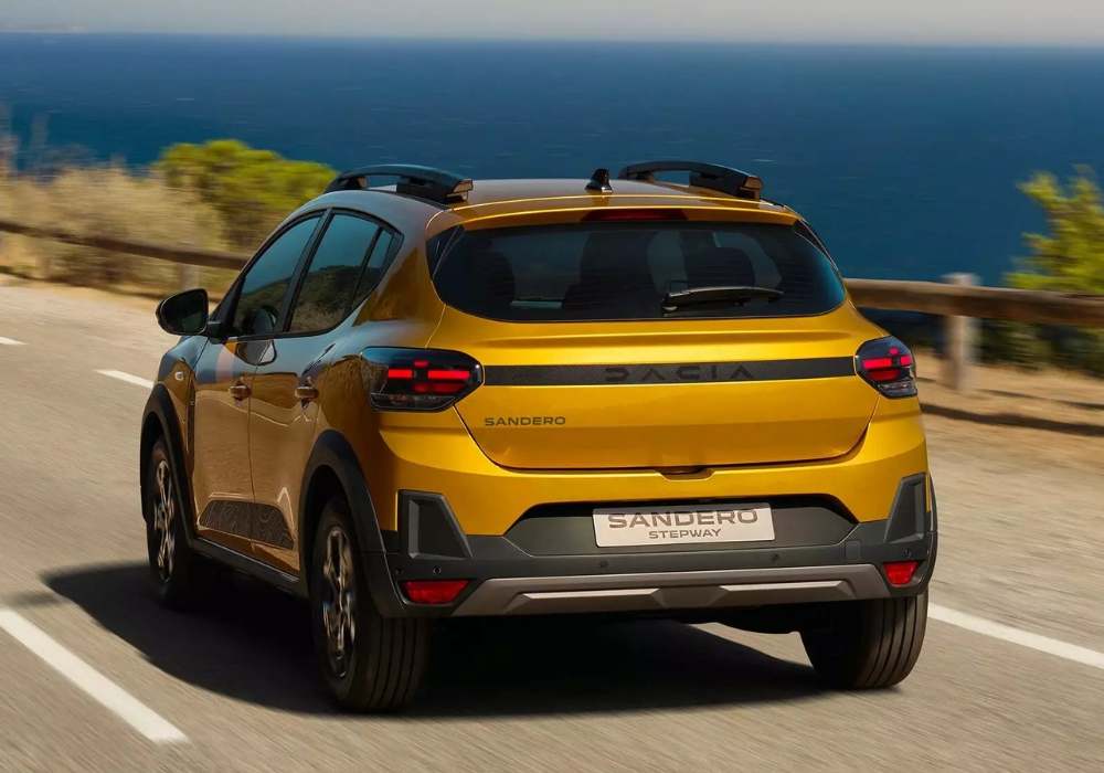 Dacia Sandero Stepway driving along a coastal road from the rear, highlighting crossover design and scenic sea views.