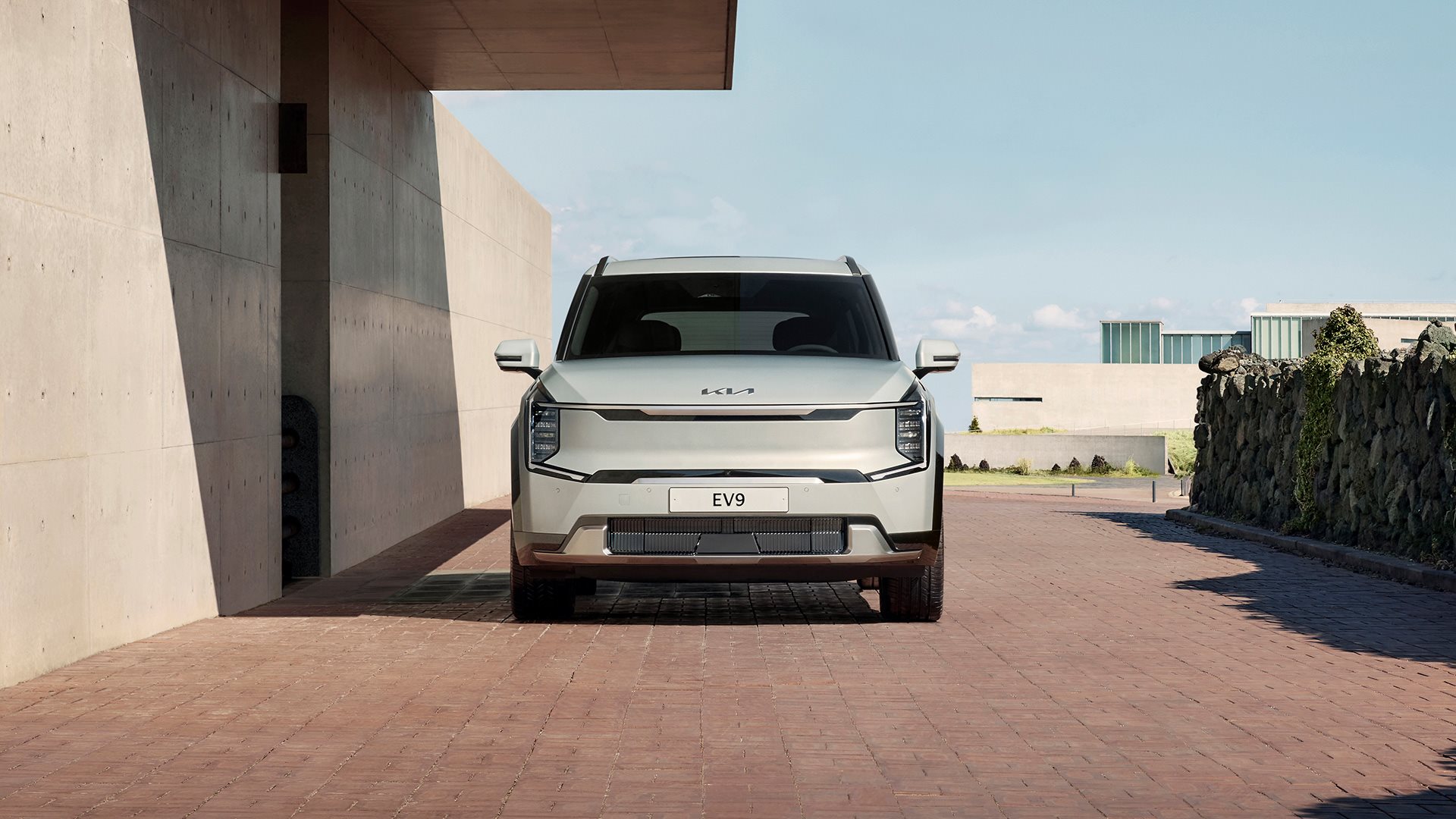 Front view of Kia EV9 parked by stone wall