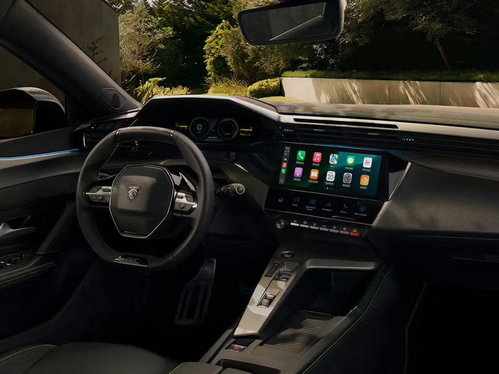 Interior view of the Peugeot 308 SW, featuring the i-Cockpit layout with compact steering wheel, digital instrument cluster and central touchscreen displaying Apple CarPlay connectivity.