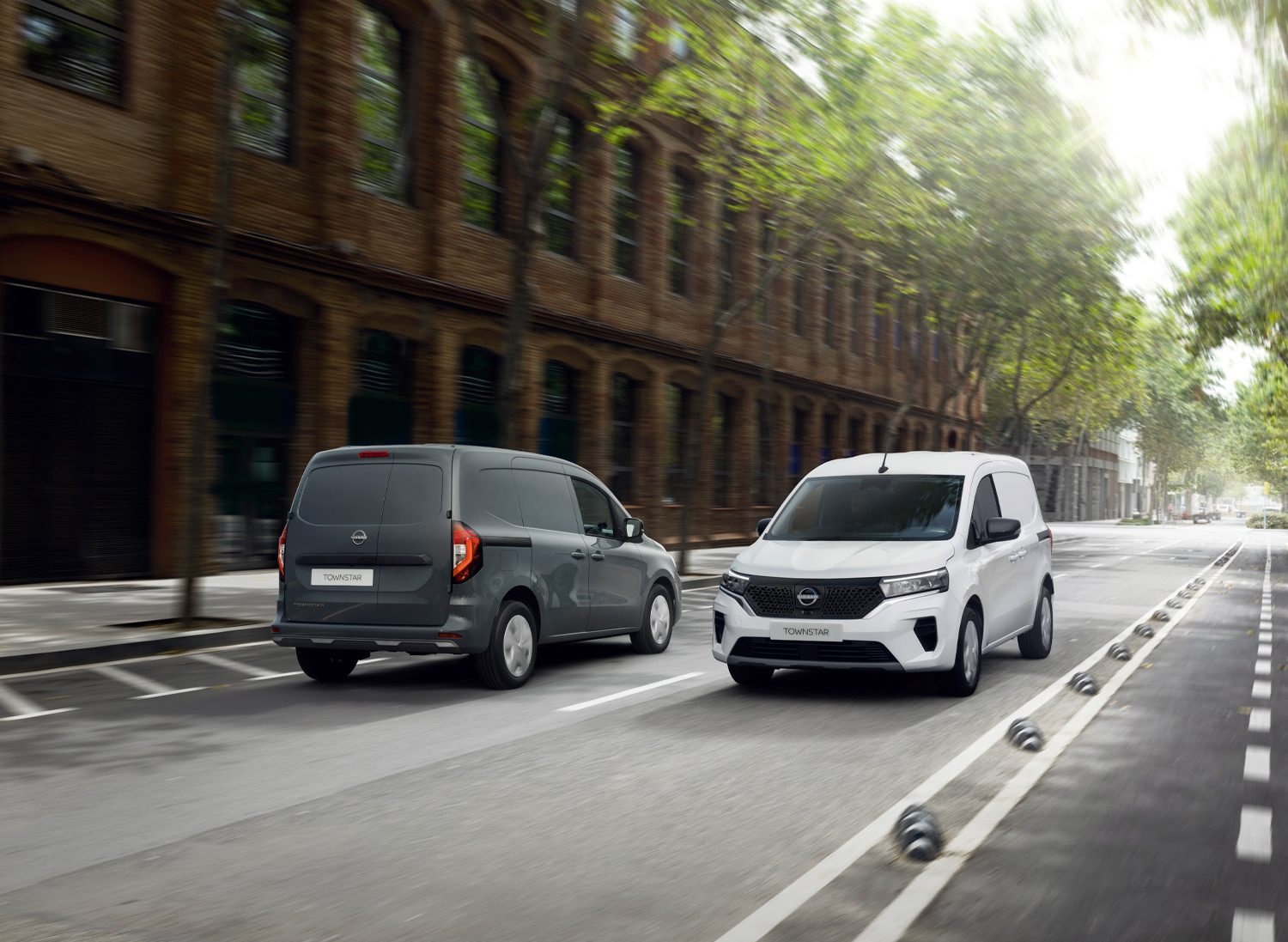 Two Nissan Townstar vans driving on a UK city street