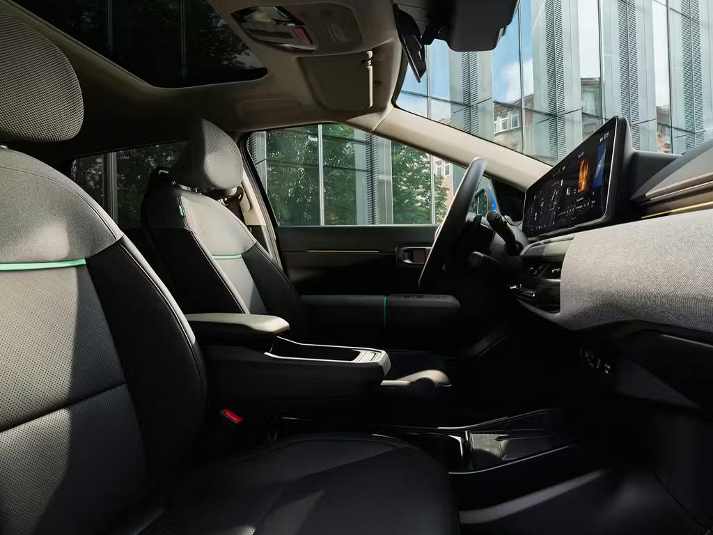 Interior view of the Kia EV4, featuring modern two-tone grey and black upholstery, curved digital display screen and minimalist dashboard design with ambient lighting accents.
