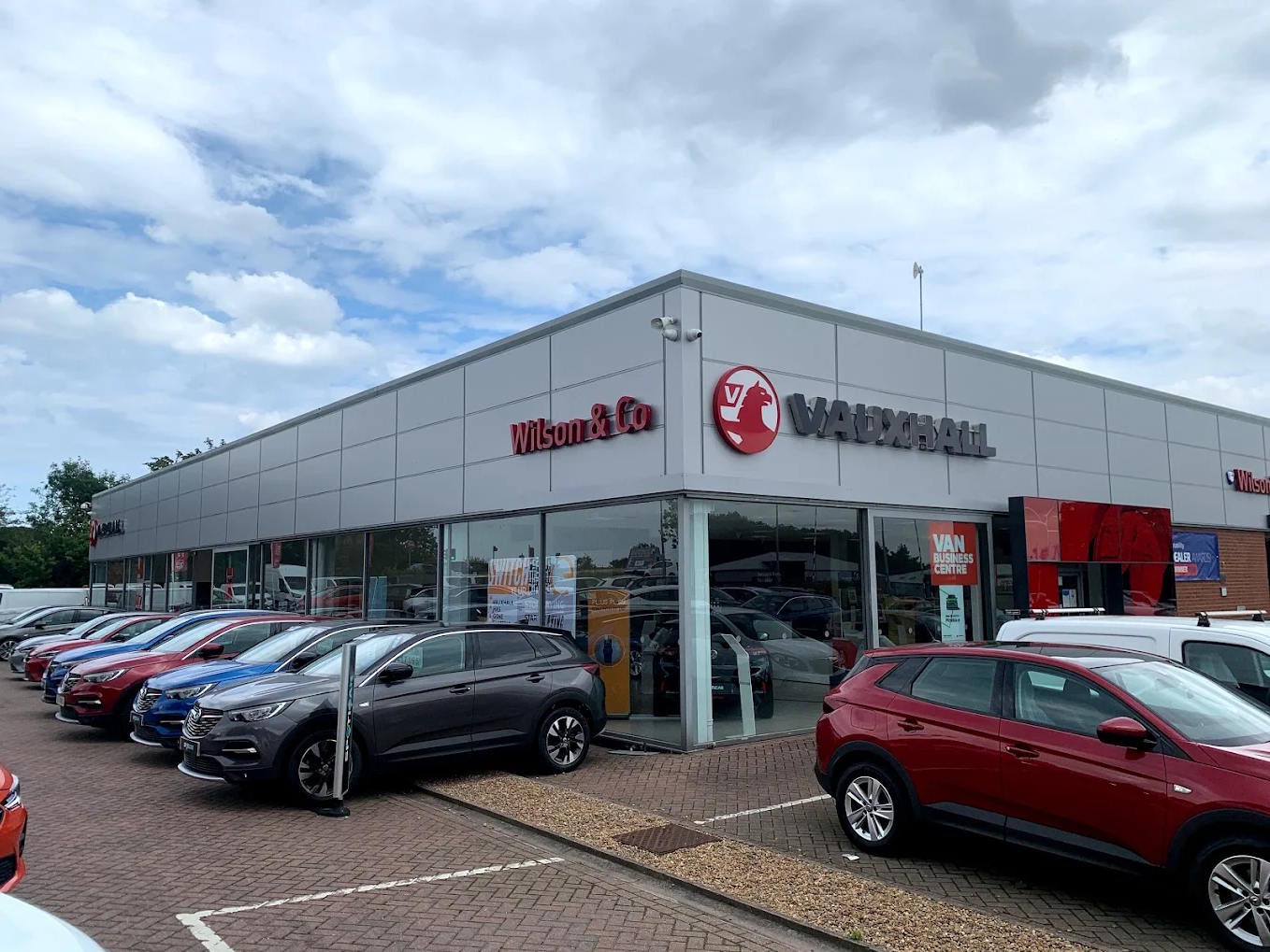 Exterior view of Wilson & Co Vauxhall Grimsby dealership, featuring a modern showroom with prominent Griffin branding and a forecourt displaying various Vauxhall models including Grandland SUVs.