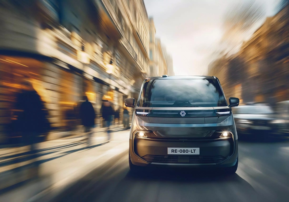 Front view of Renault Trafic E-Tech Electric van driving in an urban environment, emphasising lighting signature and dynamic motion.