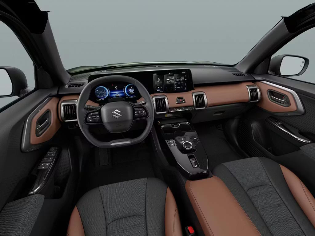 Interior cabin view of the Suzuki e Vitara, featuring a two-tone brown and black colour scheme, digital instrument cluster, central touchscreen and modern dashboard design.