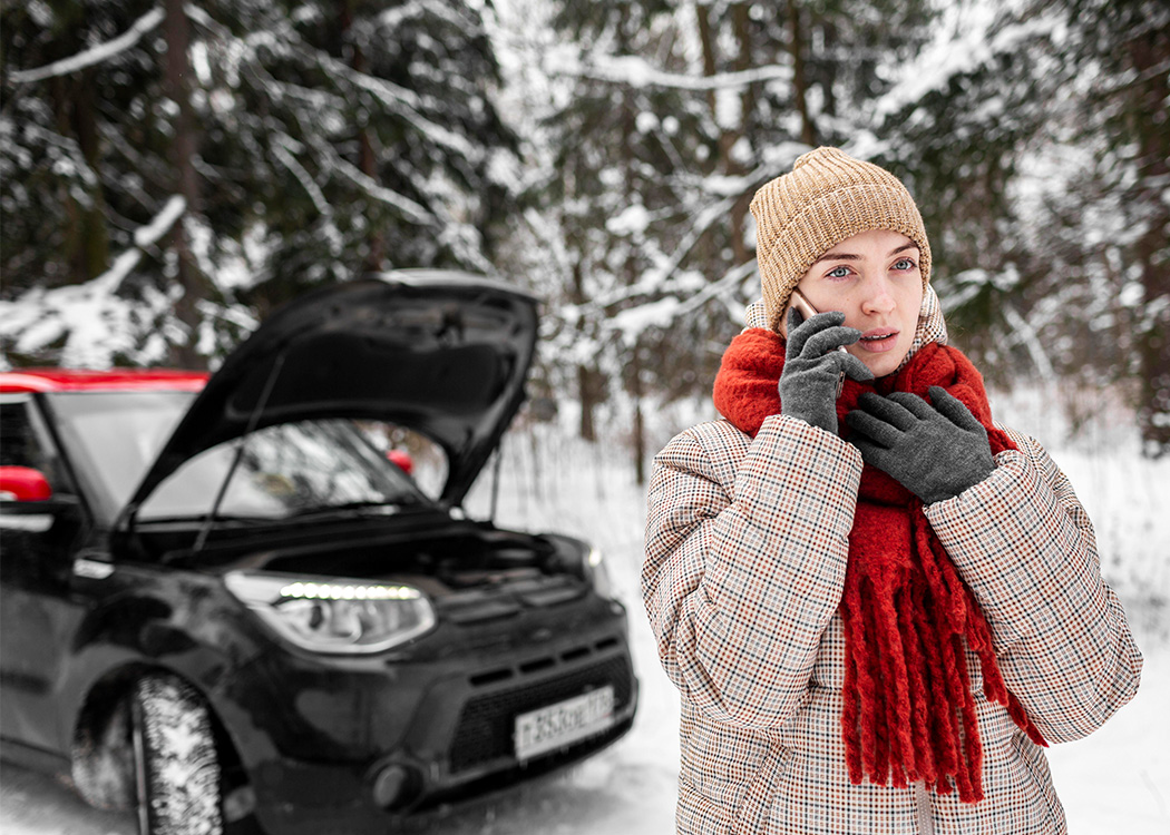 woman on phone beside car in winter snow