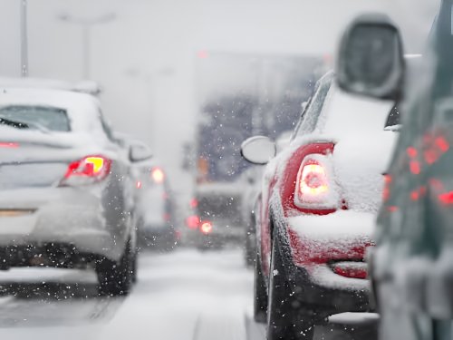 Vehicles travelling through snowy traffic during winter weather.