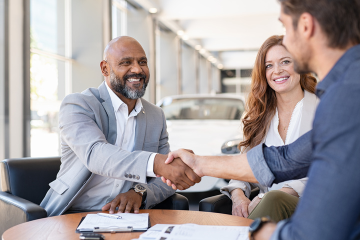 Three people having a meeting with two males shaking hands