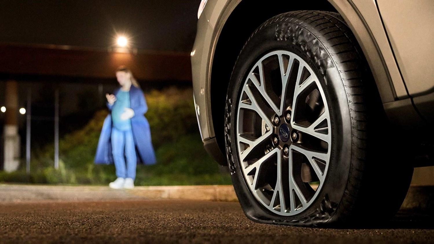 Pregnant woman waiting with a flat tyre