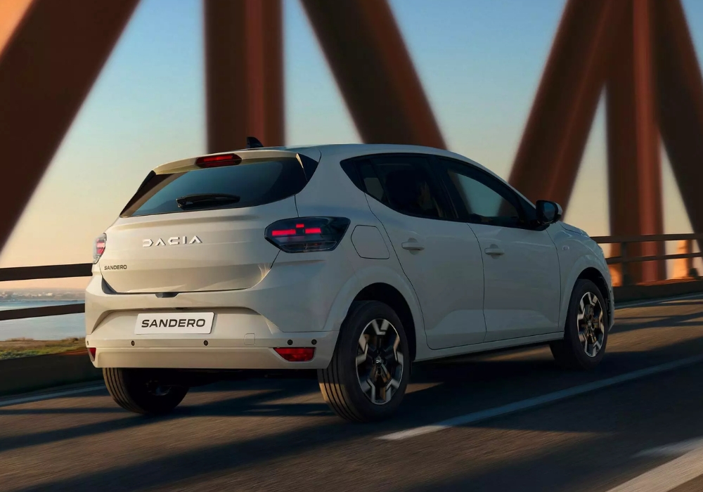 Dacia Sandero driving across a bridge from the rear, showcasing smooth performance and compact hatchback styling.