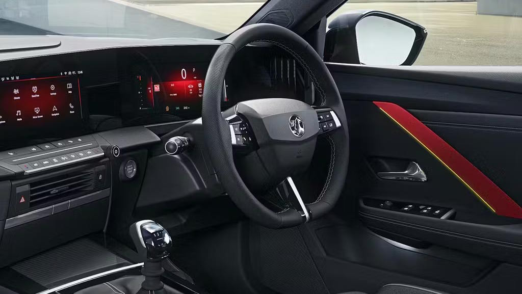 Vauxhall Astra interior featuring dual digital displays, a multifunction steering wheel and sporty red door trim detailing.
