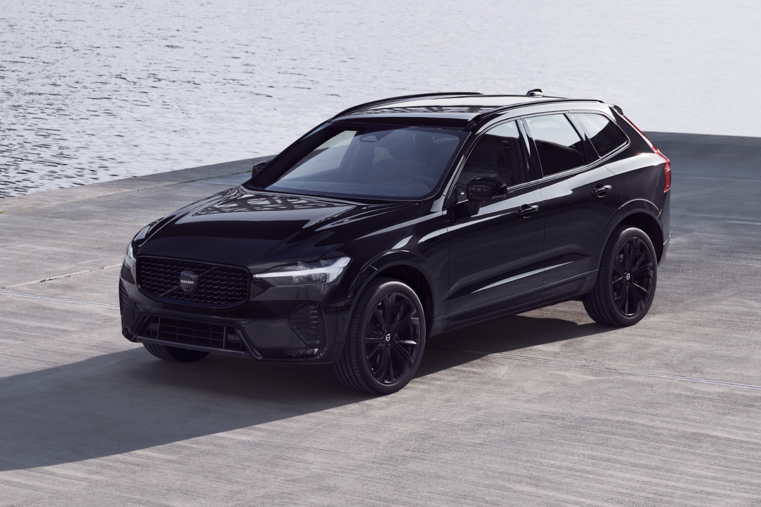 Black Volvo SUV parked by waterfront.