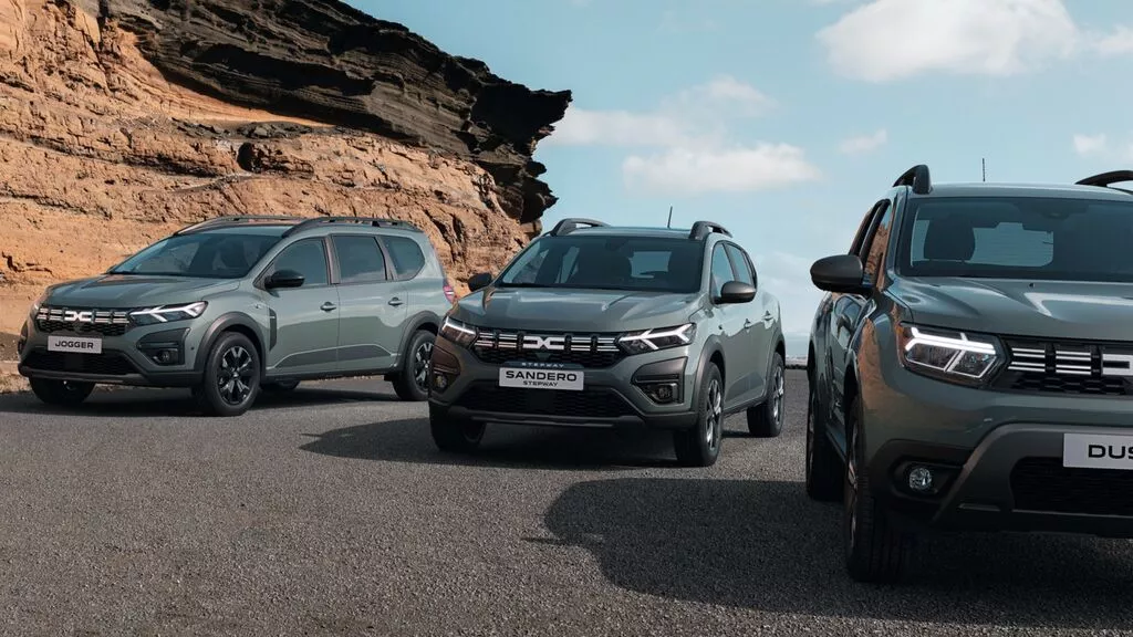 Green Dacia models parked on mountain road
