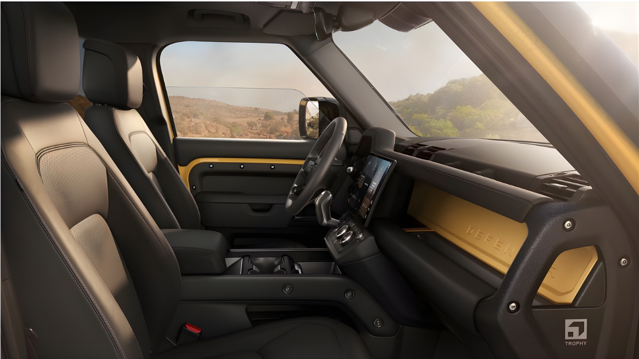 Interior view of the Defender Trophy Edition cabin with yellow dashboard trim, steering wheel, and center touchscreen.