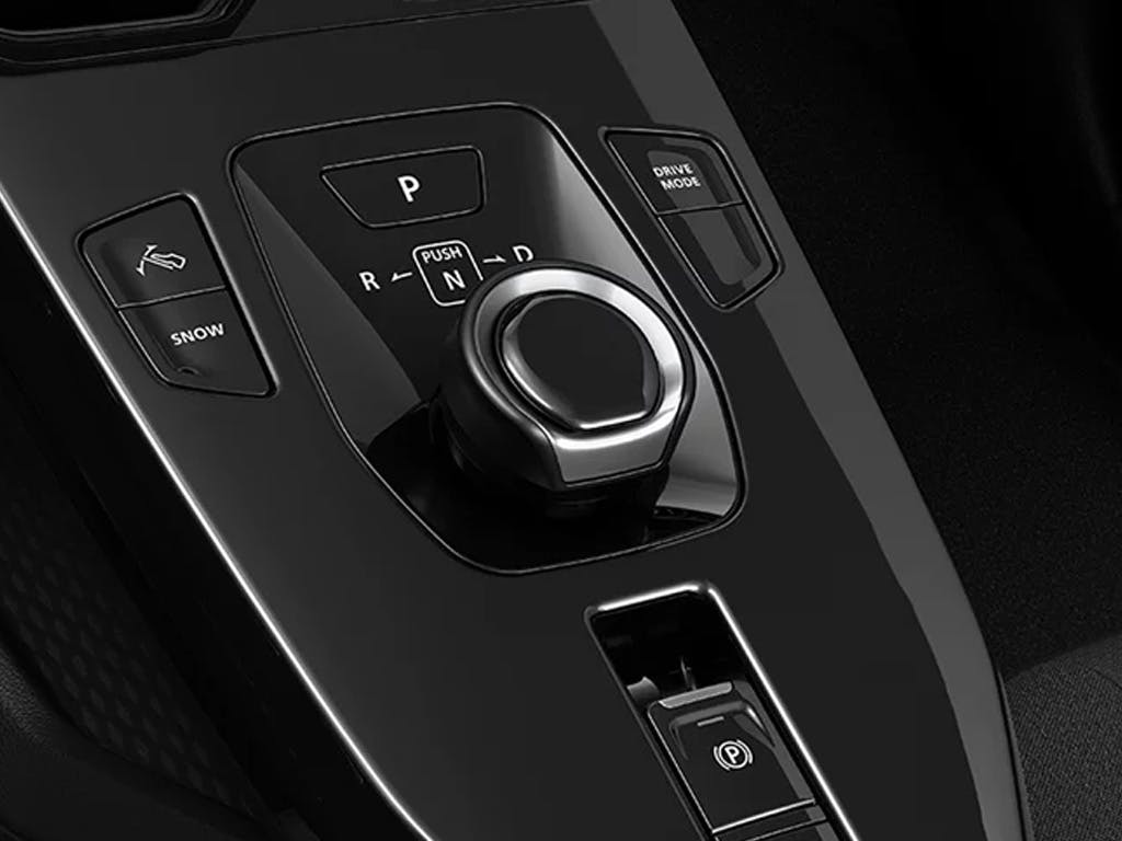 Close-up of the Suzuki e Vitara centre console featuring the rotary gear selector, electronic parking brake, drive mode button and snow mode controls in a sleek black finish.