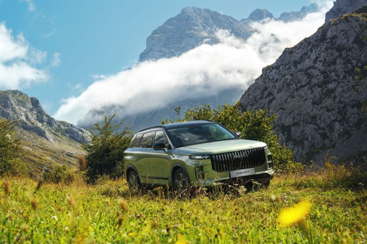 JAECOO 7 PHEV in a field with mountains in the background