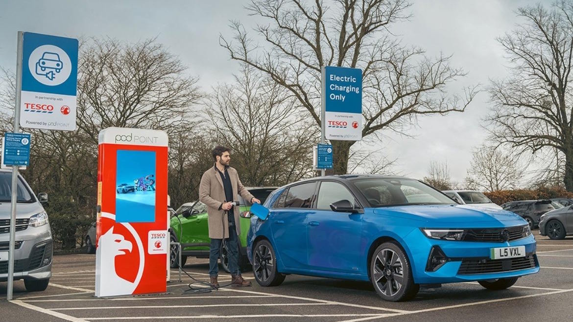 Blue Vauxhall Astra Electric plugged into a public charging point in a car park.