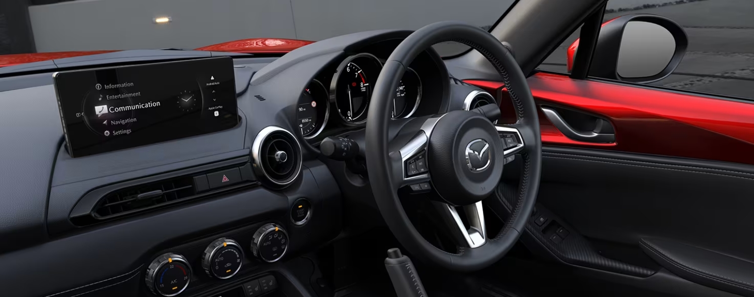 Close-up of Mazda MX 5 RF Interior with steering wheel, display screen and instrument cluster.