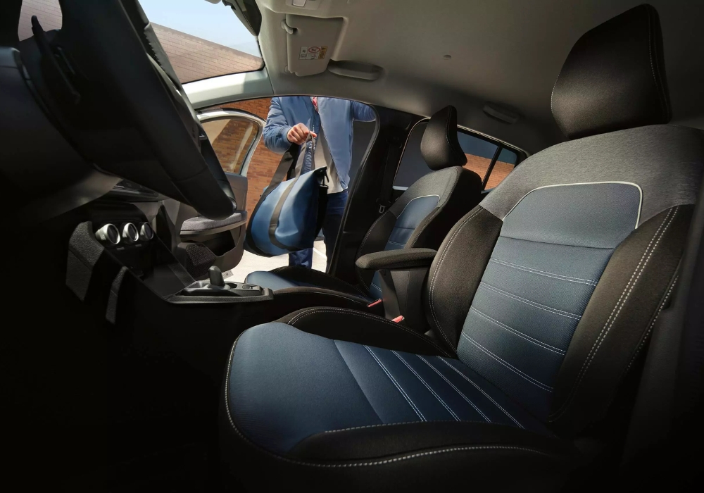 Dacia Sandero interior with front seats and open door, showing easy access and practical cabin layout.