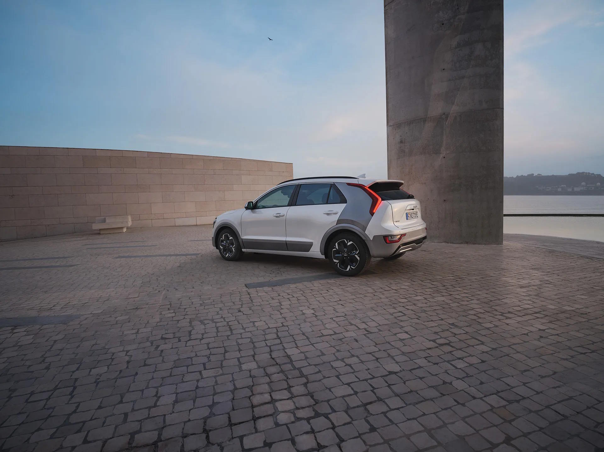 White Kia Niro EV parked in a contemporary urban setting, showcasing modern electric vehicle design and efficiency.