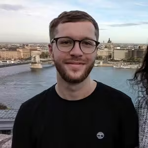 Outdoor portrait of a person wearing glasses overlooking a historic waterfront cityscape.