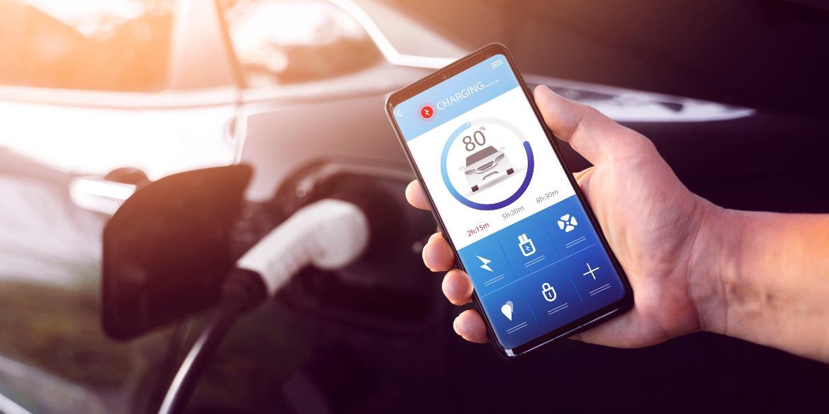 Smartphone showing electric vehicle charging status beside a plugged-in car.