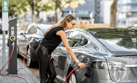 Woman charging grey car at side of road