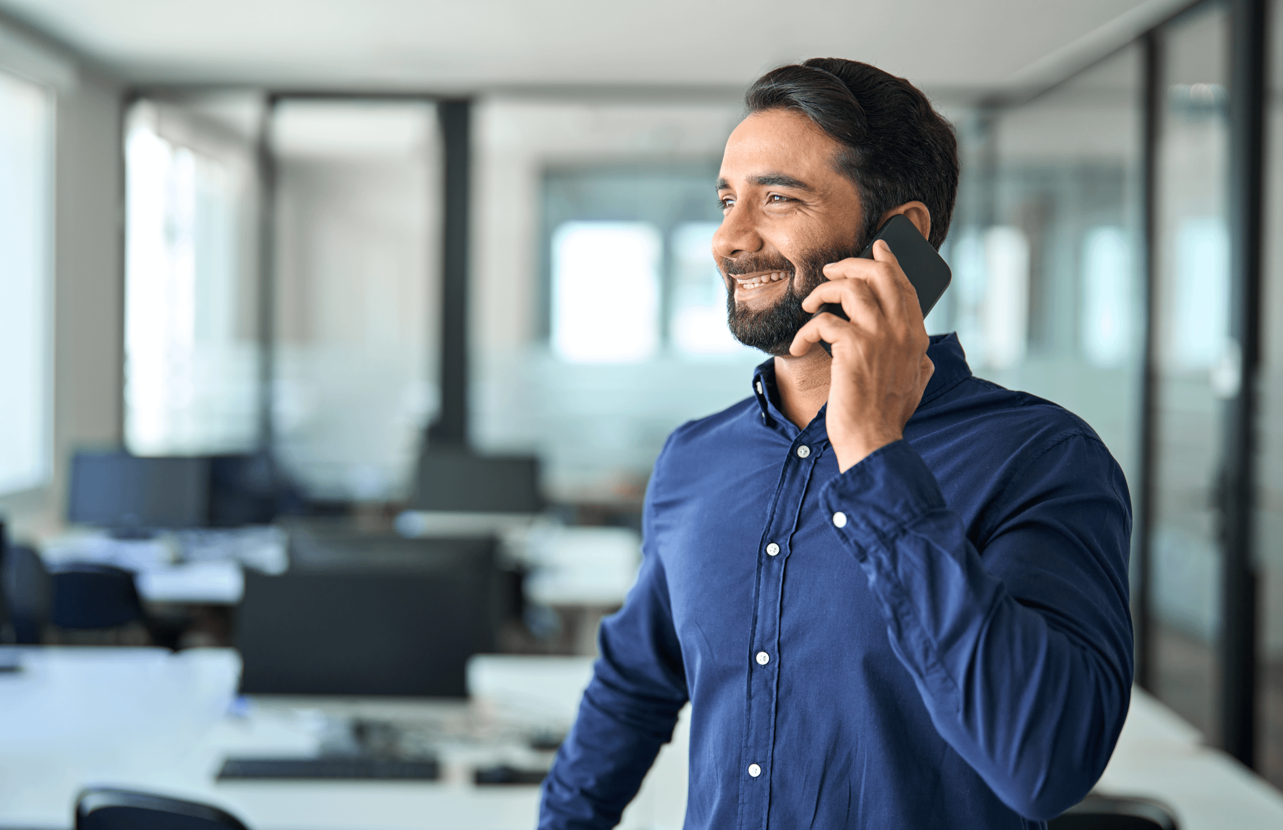 Man in navy shirt, smiling whilst on the phone.