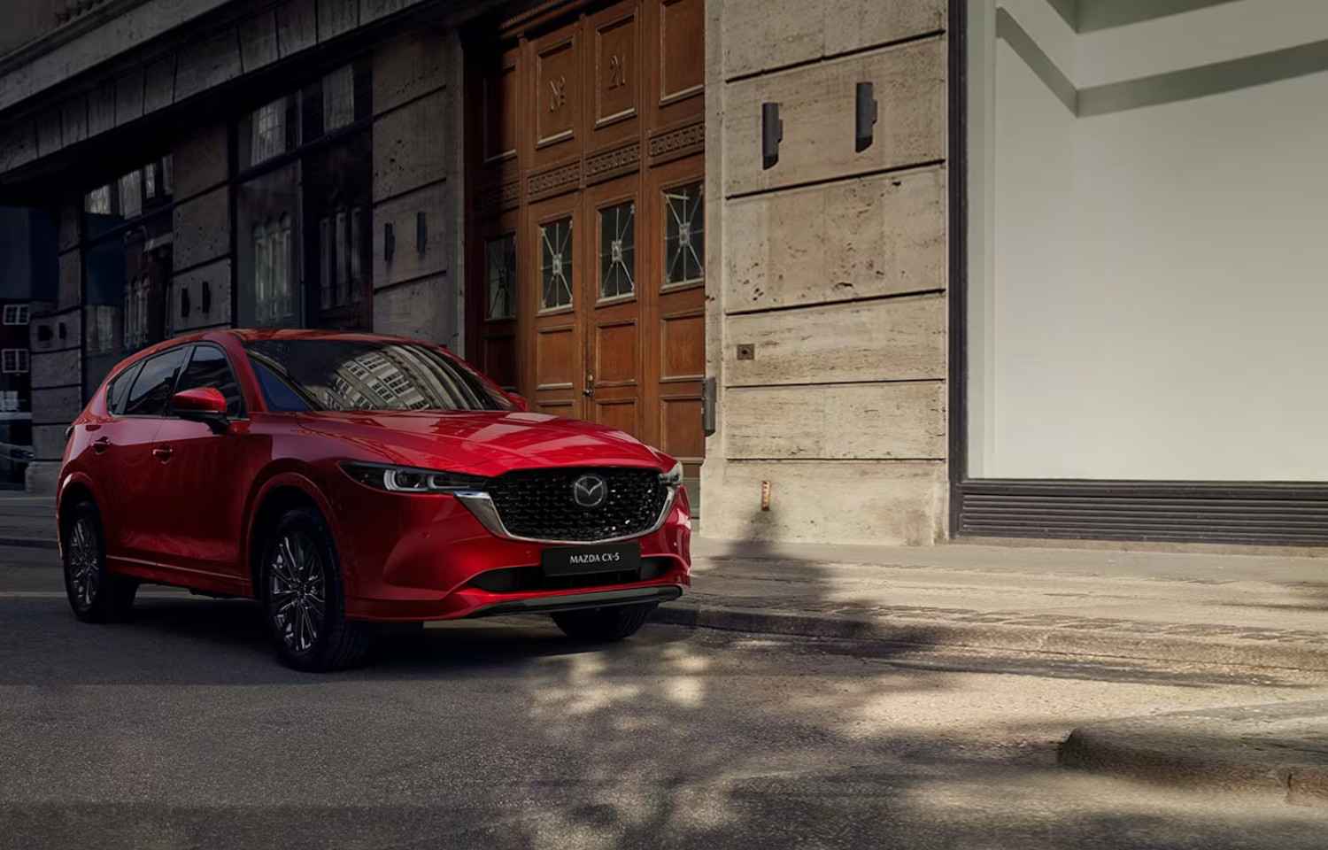 Mazda Red CX30 outside parked on a roadside near an old building