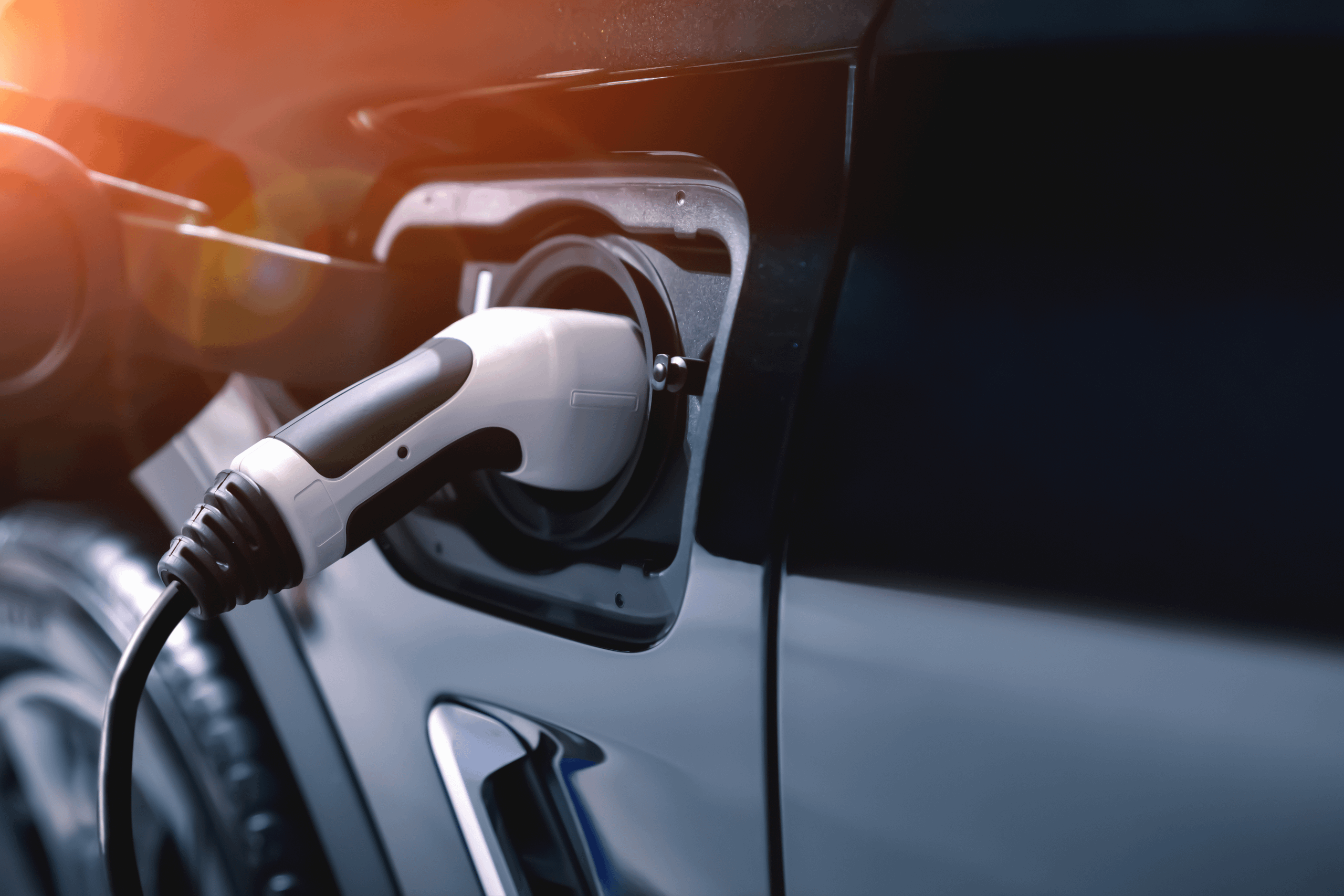 Close-up of an electric vehicle charging connector plugged into a car charging port.