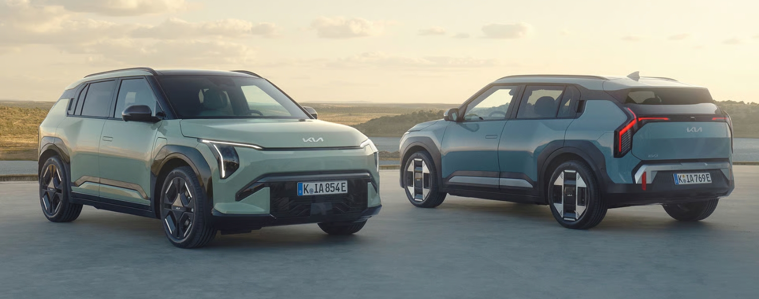 Pair of Kia cars positioned in an open outdoor setting with landscape views.