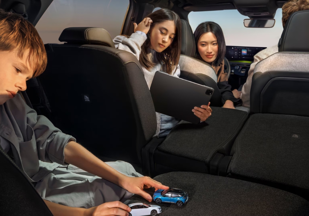 Interior of Peugeot E-5008 showing rear seating area with children and an adult using a tablet, highlighting spacious cabin.