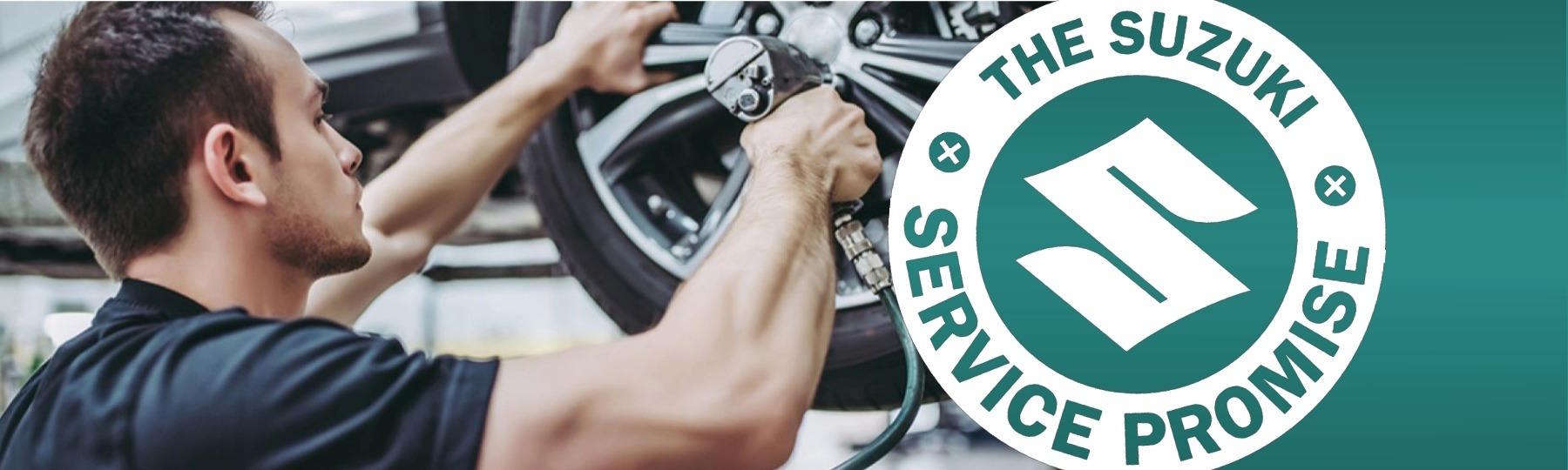 Suzuki Service Promise badge alongside a technician carefully inspecting an alloy wheel during a professional vehicle service appointment