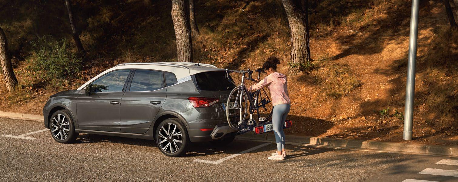 Female cyclist putting a bike on a rear-mounted bike rack on a SEAT Arona