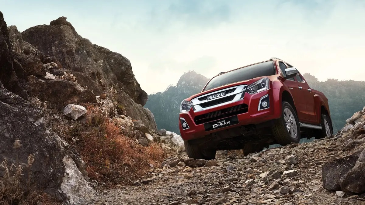 Red Isuzu D-Max driving over rocky terrain