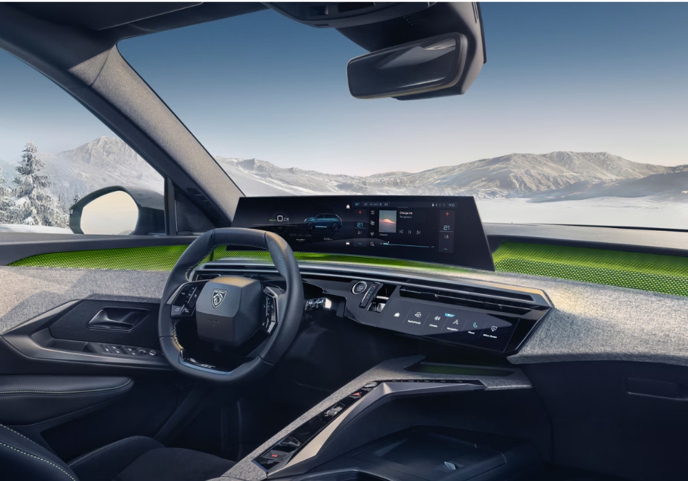 Interior cockpit of Peugeot E-5008 featuring wide curved digital display, steering wheel, and scenic mountain view through the windshield.