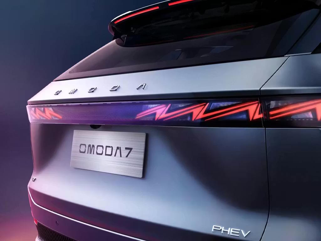 Rear close-up of the Omoda 7 PHEV, featuring a striking full-width LED light bar with angular red signature, chrome lettering and sleek two-tone bodywork.