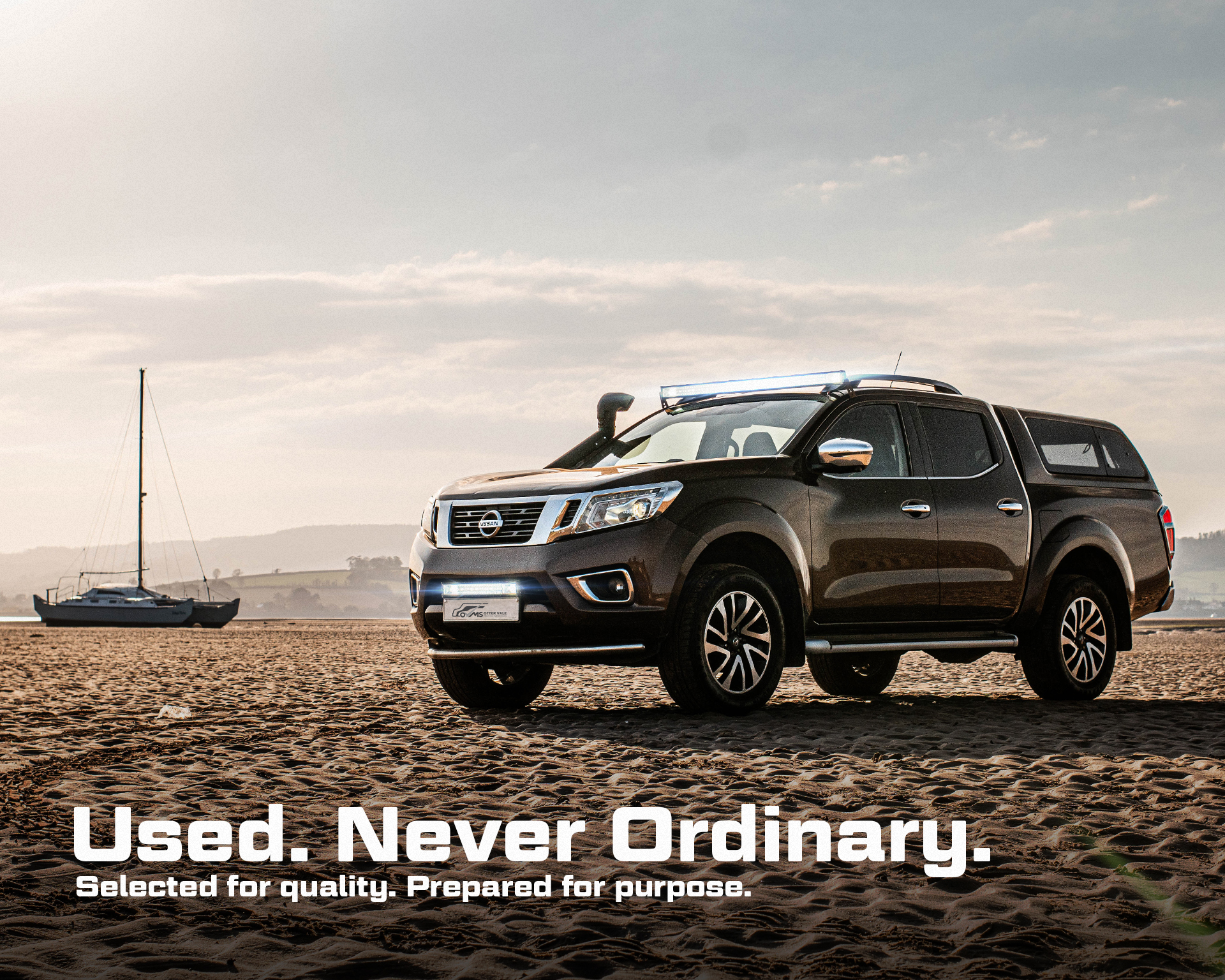 Nissan Pickup truck parked on a sandy beach. Text overlaid reading "Used. Never Ordinary. Selected for quality. Prepared for purpose".