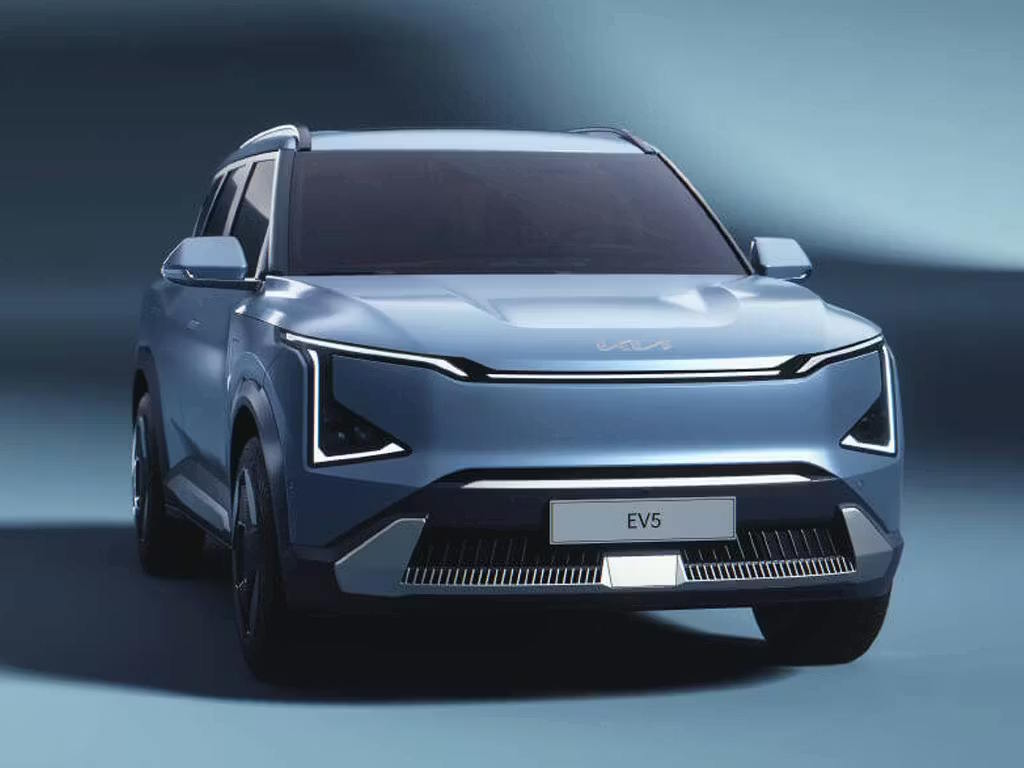 Front three-quarter view of the Kia EV5 electric SUV in pale blue, featuring bold geometric LED daytime running lights, sculpted bonnet and distinctive closed grille design.