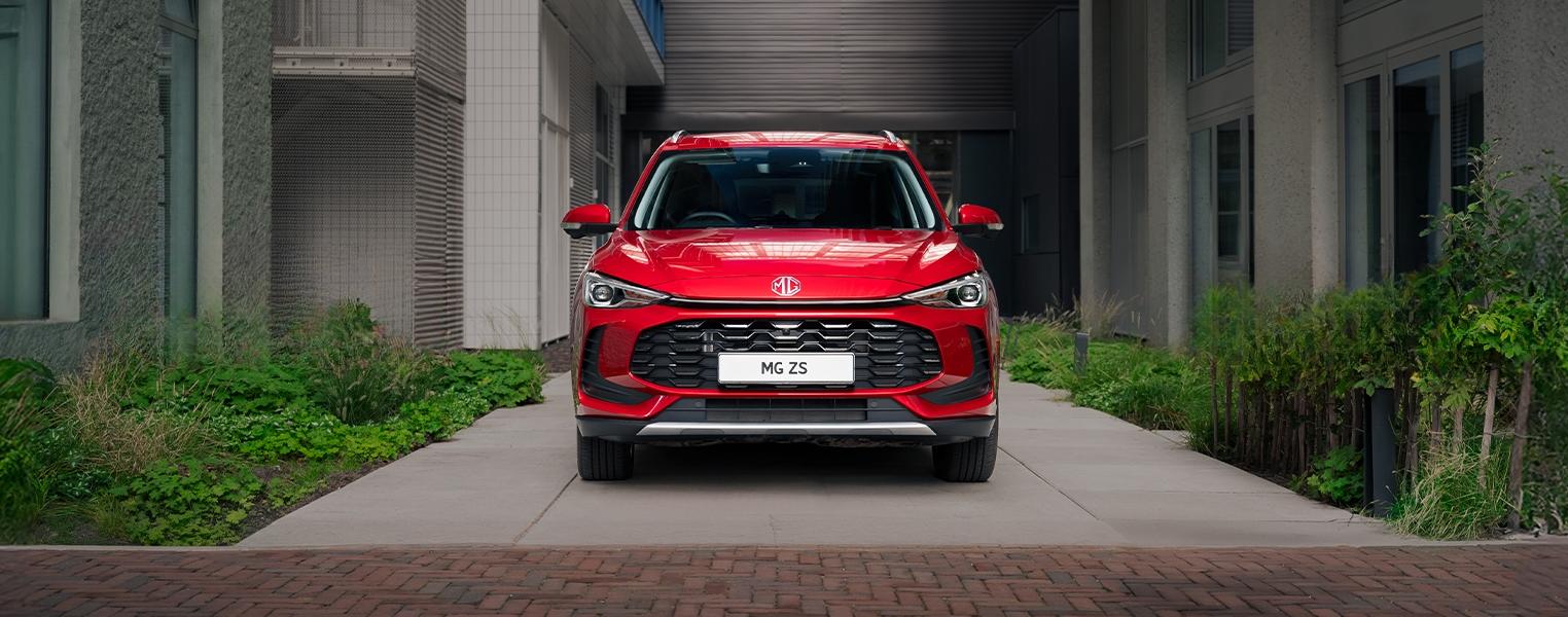 Front exterior view of a red MGZS parked outside a modern building