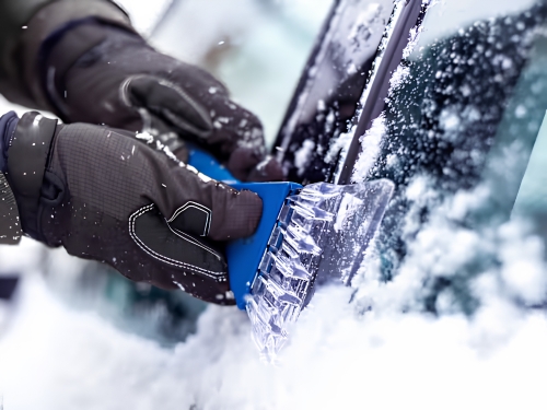 Removing ice from a vehicle windscreen with an ice scraper.