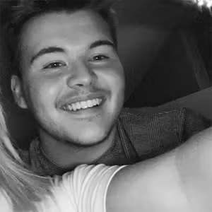 Black and white close-up portrait of a smiling person looking towards the camera.