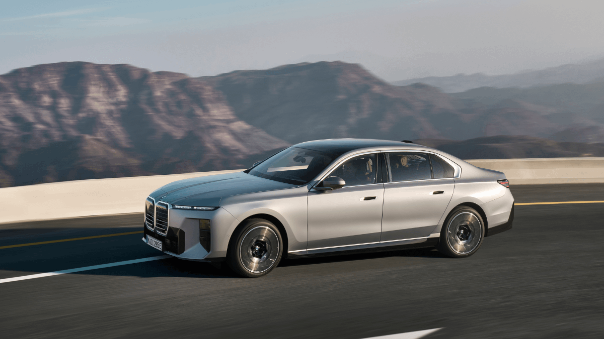 BMW i7 driving on an open road with mountains in the background, highlighting one of the best luxury electric chauffeur cars for executive travel.