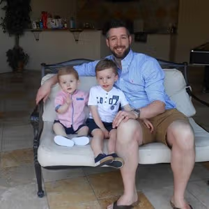 Family portrait featuring an adult and two children sitting together on a sofa.