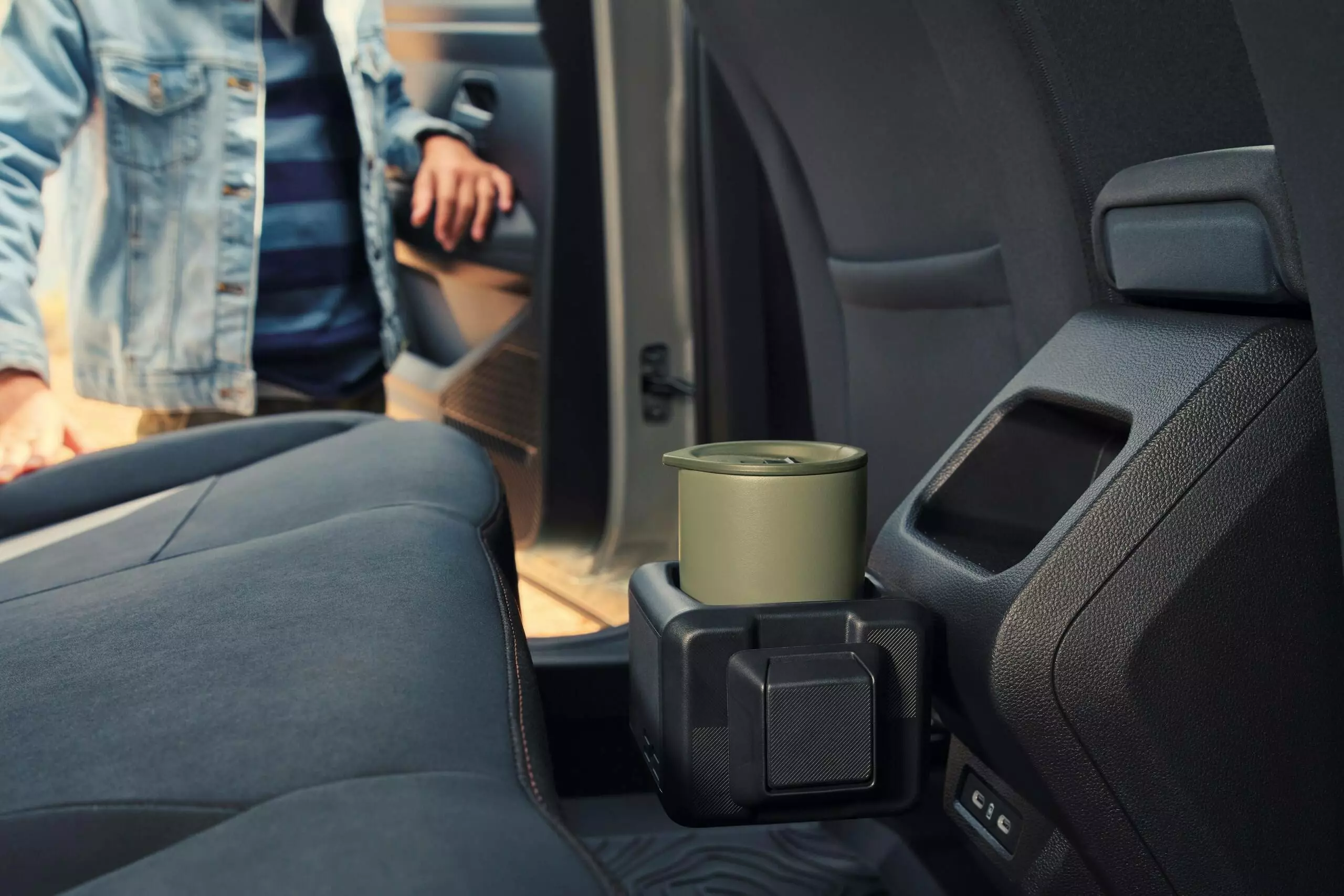 Dacia Duster rear interior with integrated cup holder and storage compartment, showing practical cabin features and seating area.