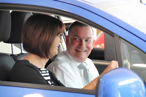 Customer enjoying a vehicle demonstration with a dealership sales advisor.