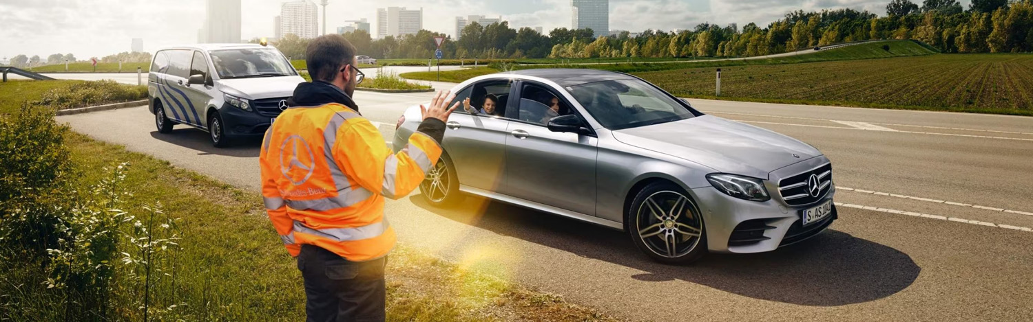 Person in high visibility jacket waving off person in Silver Mercedes-Benz