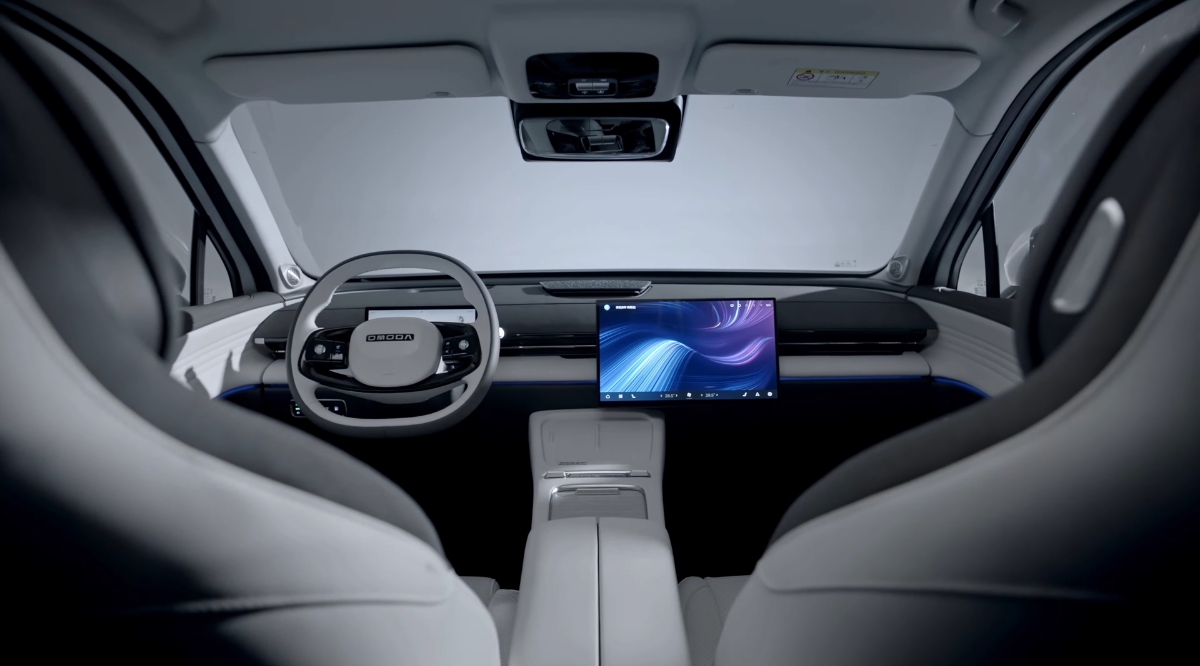 Minimalist OMODA 5 interior featuring a wide digital display, steering wheel, and clean dashboard design viewed from the rear seats.