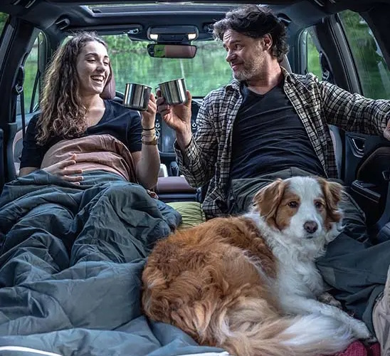 Lady, man and a dog camping in a Subaru Forester