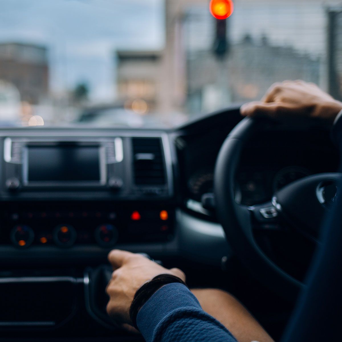 Driver holding the steering wheel inside a van with dashboard controls visible.