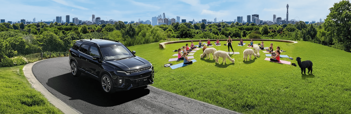 Black KGM Actyon Hybrid driving through a park with people doing yoga in the background with alpacas